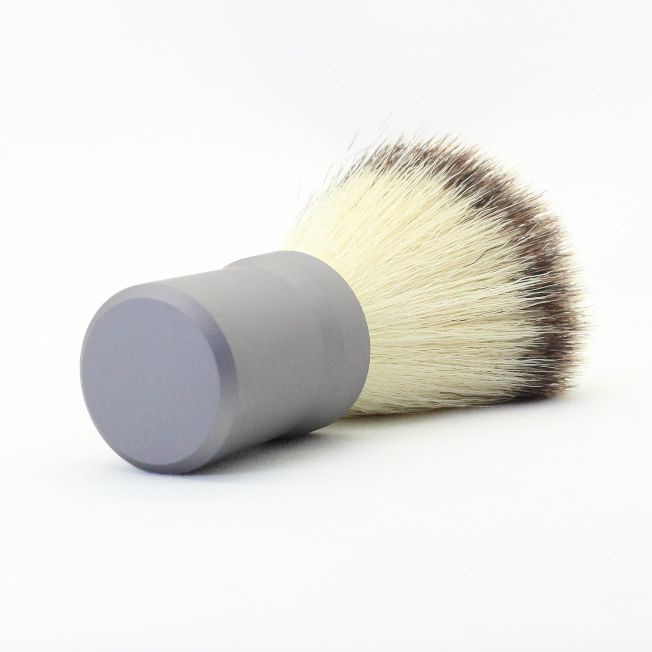 Shaving brush with gray handle and white bristles on a white background