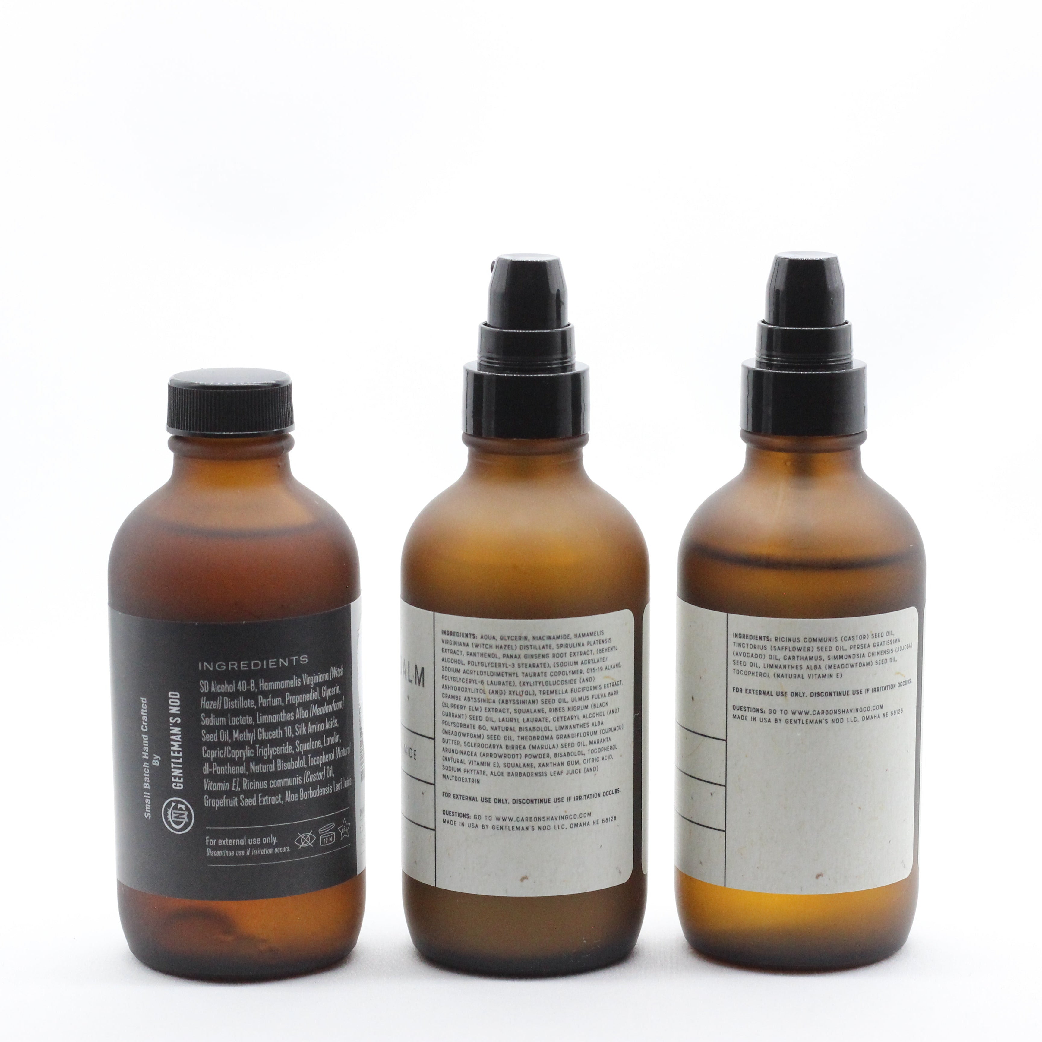 Three amber glass bottles with black sprayers on a white background